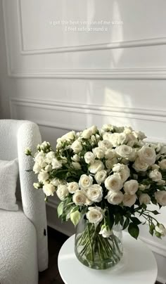 a vase filled with white flowers sitting on top of a table next to a chair