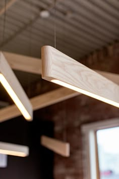 the lights are hanging from the ceiling in the room with exposed brick walls and wooden beams