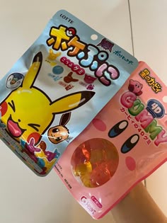 two packets of gummy are sitting on someone's hand, one has a pikachu and the other has an egg in it