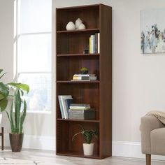 a living room scene with focus on the bookshelf and plant in the foreground