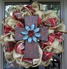 a wreath with a cross hanging from it's center and burlocks on the front door