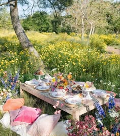 a picnic table is set up in the middle of a field with flowers and trees