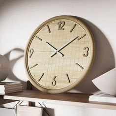 a wooden clock sitting on top of a shelf next to a vase and bookcase