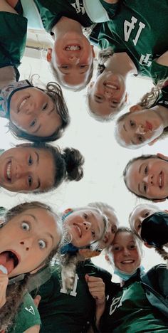 a group of young women standing in a circle with their mouths open and hands together