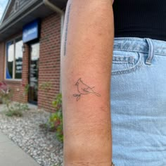 a person with a small tattoo on their arm, standing in front of a brick building