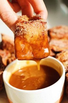 a person dipping some kind of food into a bowl filled with sauce on top of it