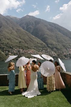 a group of women standing on top of a lush green field next to a lake