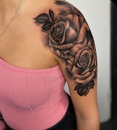 a woman's shoulder with roses on it and leaves in the middle of her arm