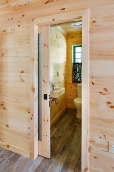 an open door leading to a bathroom with wood walls