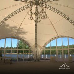 a large white tent with chandelier hanging from it's ceiling and windows