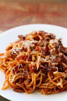 a white plate topped with spaghetti covered in sauce and meats on top of it