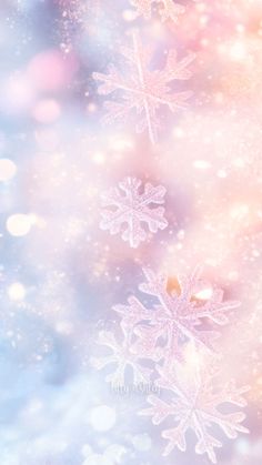 snow flakes are floating in the air on a blue and pink blurry background