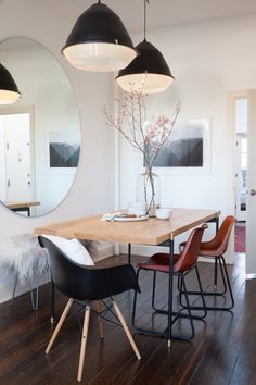 a dining room table with four chairs and a mirror on the wall in front of it