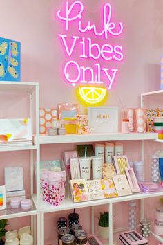 pink vibes only neon sign in the corner of a room with shelves full of items