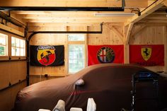 the inside of a garage with several cars parked in front of it and flags hanging on the wall