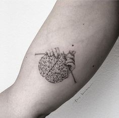 a person with a needle and brain tattoo on their arm