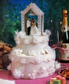 a wedding cake with a bride and groom figurine on top, surrounded by wine glasses