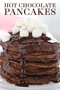 a stack of chocolate pancakes covered in marshmallows on top of a white plate