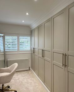 an empty room with white furniture and large window blinds on the windowsill, in front of a radiator