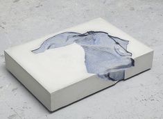 a piece of artwork is placed on the ground in front of a concrete block with a blue shirt drawn on it