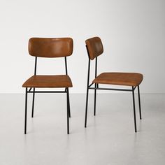 two brown chairs sitting next to each other on top of a white floor in front of a wall