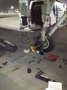 an airplane is parked on the tarmac with tools and other items scattered around it