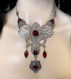 "This elegantly ornate necklace is made with light weight, antique silver tone filigrees and pendants, featuring romantic scrolls and beautifully balanced details. Its mesmerizing design is accented with dazzling dark ruby red glass crystals/jewels. Decorated portion is 6 1/2\" wide and 4 3/4\" tall in the very center. Necklace length is adjustable 15\"-18\" with soldered stainless steel cable chain, lobster clasp and extender. If you would like a different length, please send us a message. Matc Red Metal Filigree Jewelry, Antique Silver Filigree Metal Necklace, Gothic Metal Necklace With Intricate Design, Ornate Red Filigree Jewelry, Ornate Filigree Silver Bridal Necklace, Ornate Silver Bridal Necklace, Gothic Filigree Necklace For Wedding, Gothic Wedding Necklace With Filigree Detail, Gothic Filigree Wedding Necklace