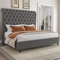 a large bed sitting on top of a wooden floor next to a wall with pictures above it