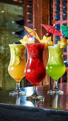 three different colored cocktails sitting on top of a table