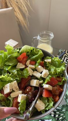 a salad with lettuce, tomatoes and feta cheese in a metal bowl