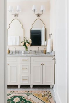 a bathroom with two sinks, mirrors and rugs on the floor in front of it