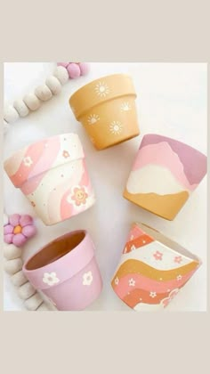 four flower pots sitting next to each other on top of a white table with beads