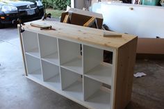 a white bookcase sitting on top of a wooden floor next to a black car