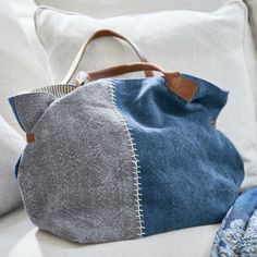 a blue and grey purse sitting on top of a white couch next to a pillow