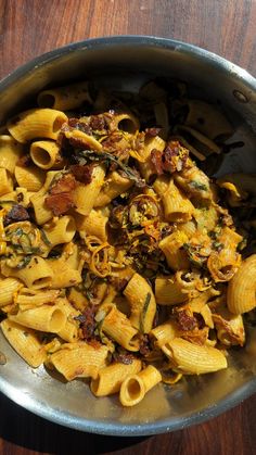 a bowl filled with pasta and sauce on top of a wooden table