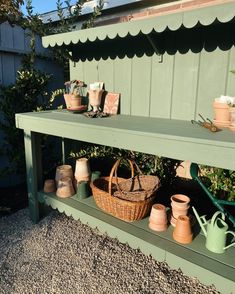 a green bench with pots and baskets on it