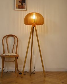 a wooden floor lamp sitting next to a chair on top of a hard wood floor