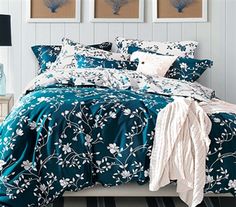 a bed with blue and white comforters in a room next to two pictures on the wall