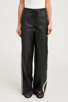 A take on an athletic track pant made entirely out of buttery-soft leather. This wide-leg silhouette has a relaxed fit with 2 white athletic stripes down the sides for a chic, sporty look. These pants are made in signature French stretch-leather, so they feel like a second-skin and are extremely breathable for year-round wear. The adjustable drawstring allows for versatility and can be worn fitted to the waist, as desired. 100% French Lambskin Stretch Leather - Cotton-Lycra lining Eco friendly, Leather Drawstring Pants, Formal Dress Jacket, Ladylike Dress, Athletic Sweatpants, Sweatpants Black, Leather Pant, Closet Makeover, Track Pant, Straight Leg Denim