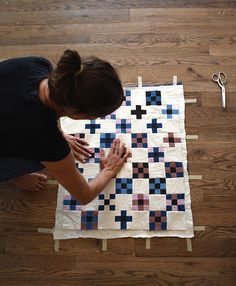 a woman is making a quilt on the floor