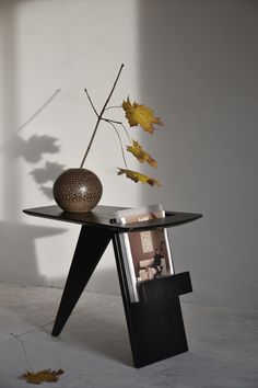 a table with a vase on it and some leaves in front of the glass top