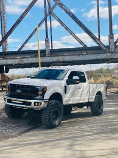 a white truck is parked in front of a bridge