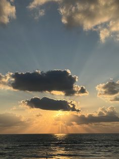 the sun is shining through clouds over the ocean