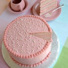 a pink cake sitting on top of a white plate next to a cup and saucer