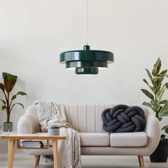 a living room with a white couch and green lamp hanging from it's ceiling