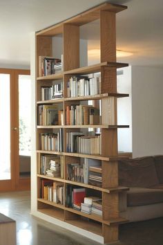 a bookshelf filled with lots of books next to a couch