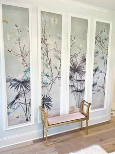 a bench sitting in front of three wall paintings with flowers on the back and one behind it