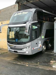 a silver bus parked in front of a building next to a parking lot with an open door