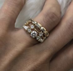 a woman's hand wearing a gold ring with three stones on it and two diamonds in the middle