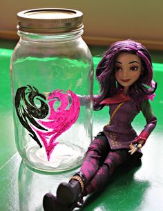 a doll sitting next to a glass jar filled with water and pink heart painted on it